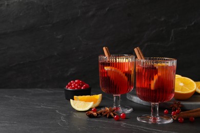 Photo of Aromatic punch drink and ingredients on black table, space for text