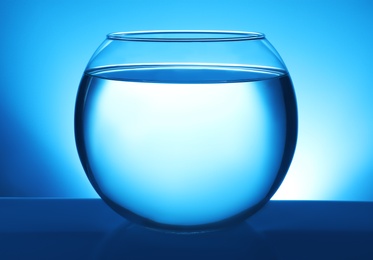 Photo of Glass fish bowl with clear water on blue background