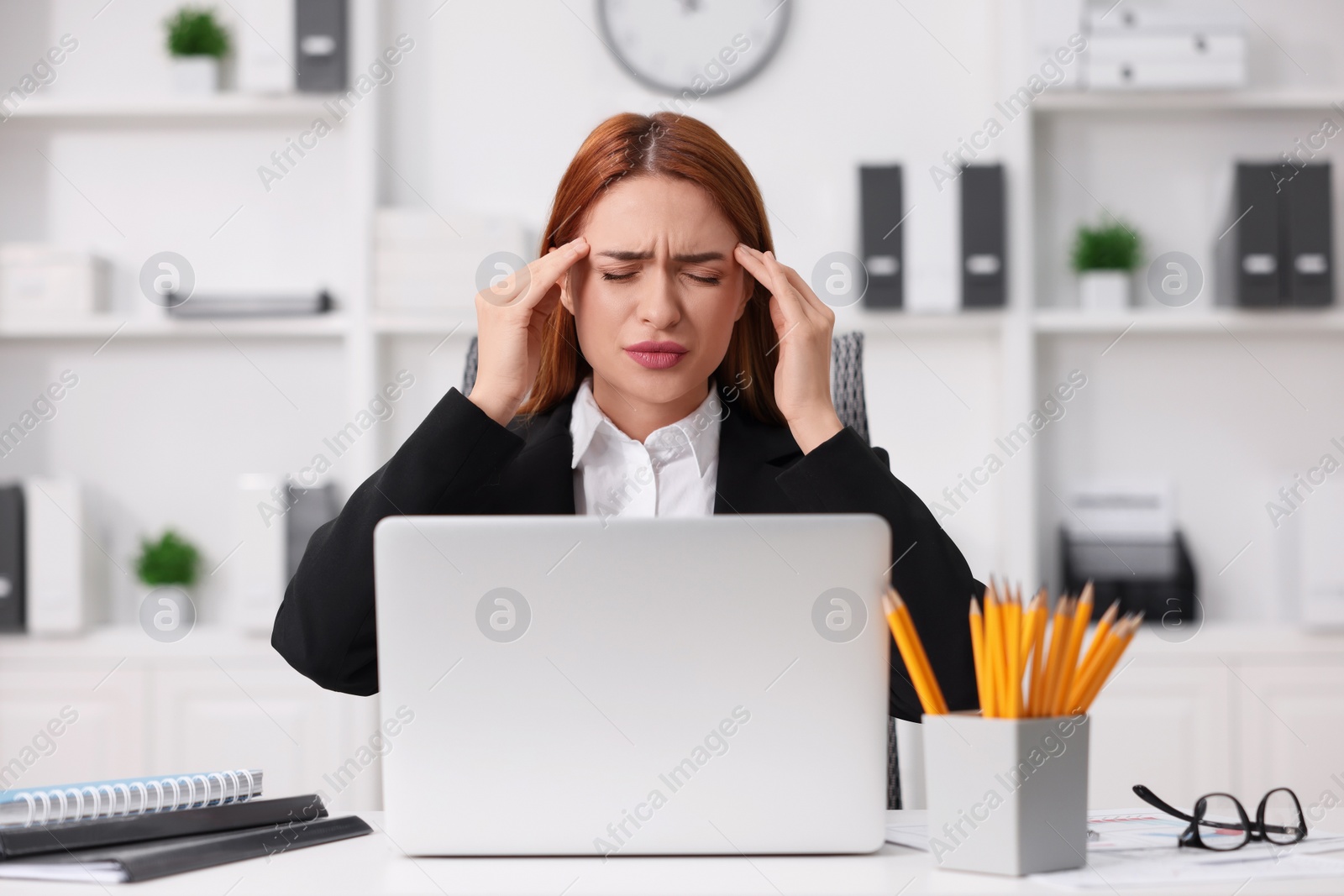 Photo of Woman suffering from headache at workplace in office