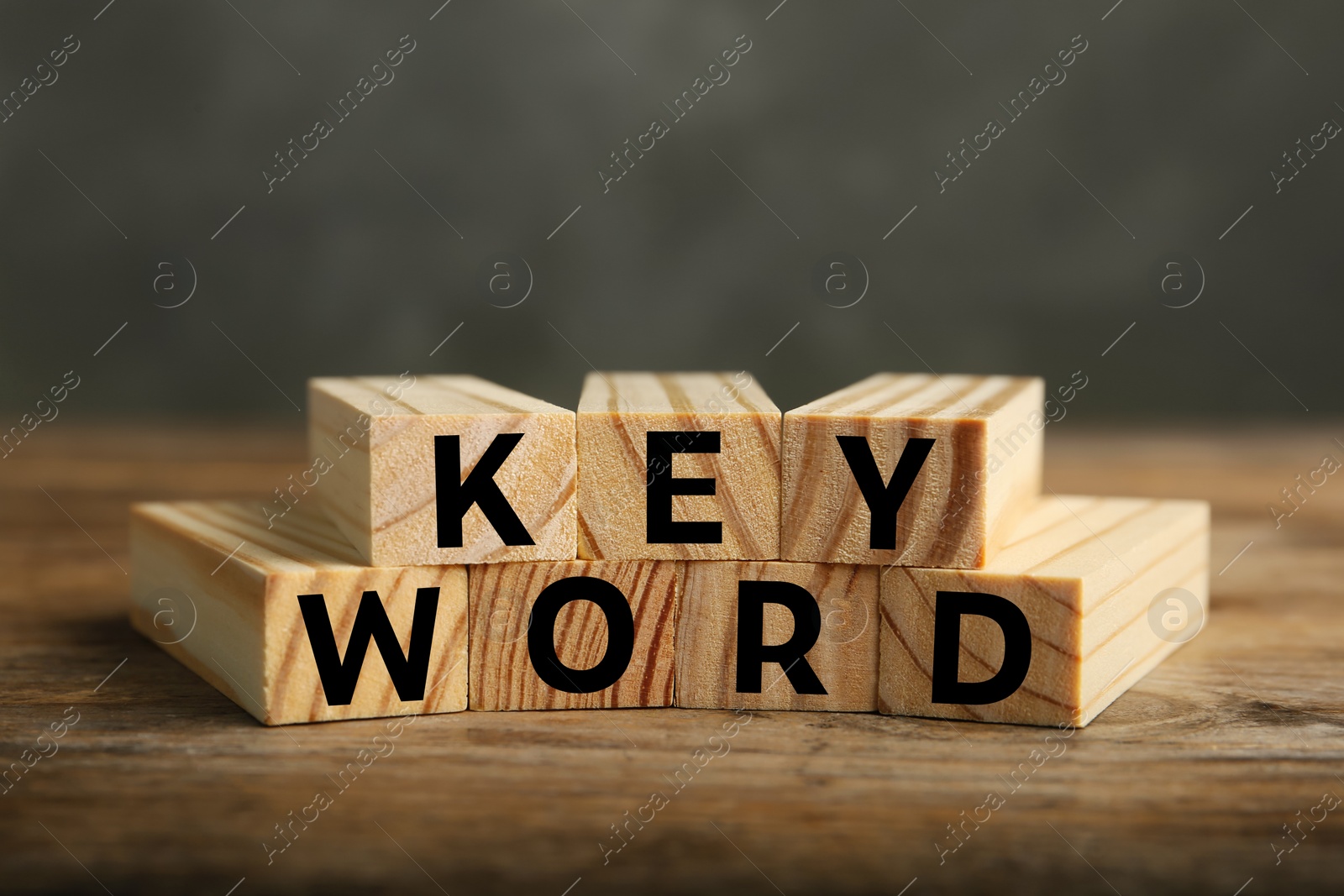 Photo of Word KEYWORD made of blocks on wooden table, closeup
