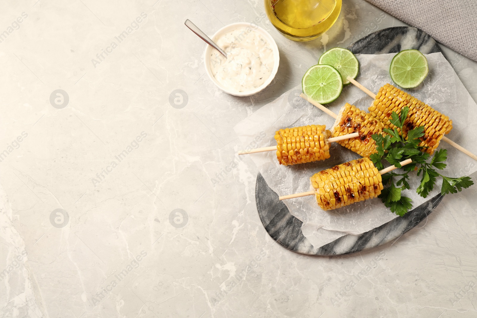 Photo of Tasty grilled corn on light grey table, flat lay. Space for text