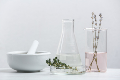 Photo of Ingredients for herbal cosmetic products and  laboratory glassware on white table