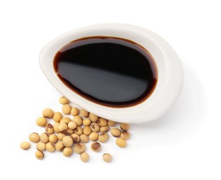 Tasty soy sauce in gravy boat and soybeans isolated on white, top view