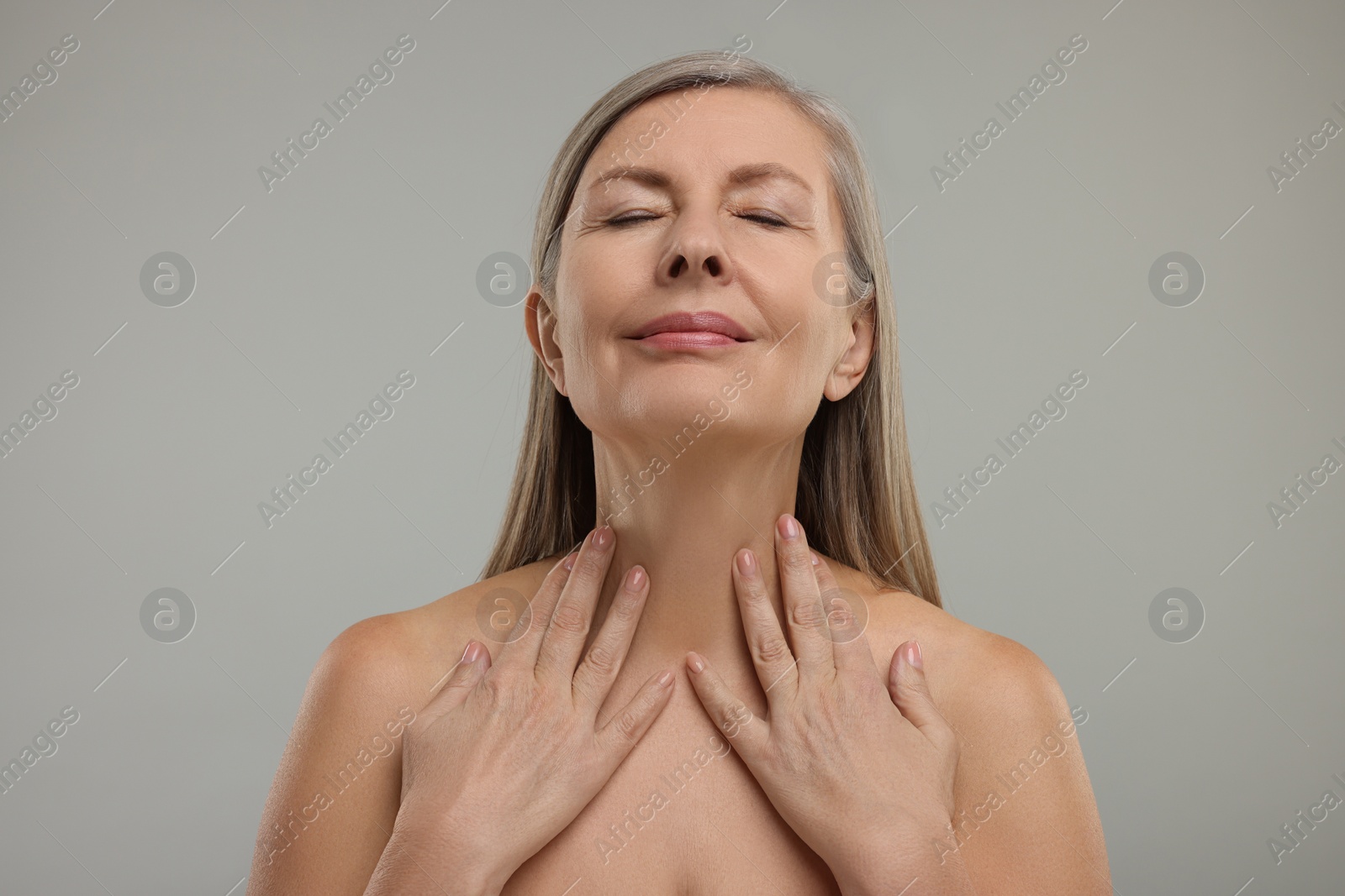 Photo of Beautiful woman touching her neck on grey background