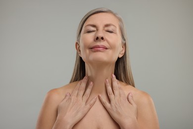 Beautiful woman touching her neck on grey background