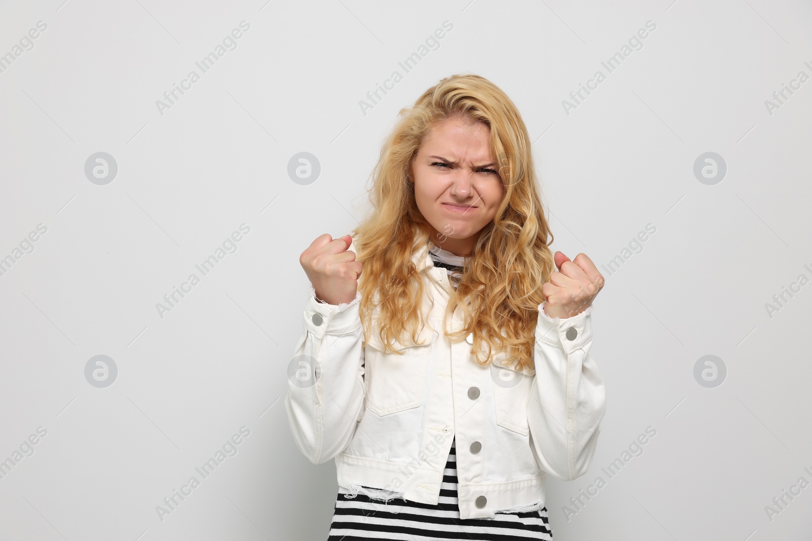 Photo of Aggressive young woman clenching fists on white background