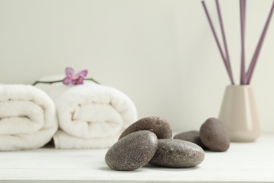 Photo of Pile of spa stones on white wooden table