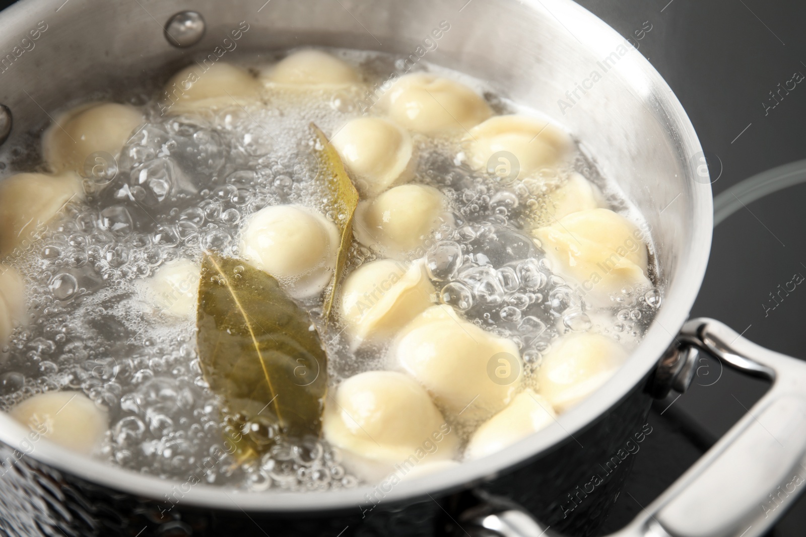 Photo of Closeup of metal stewpan with boiling water and dumplings. Home cooking