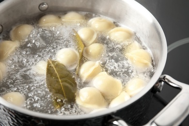 Photo of Closeup of metal stewpan with boiling water and dumplings. Home cooking