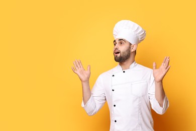 Surprised chef in uniform on yellow background. Space for text