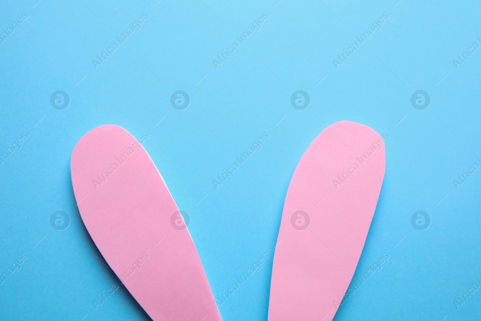 Photo of Top view of paper bunny ears on blue background. Easter celebration