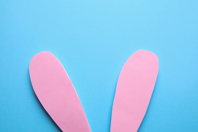 Photo of Top view of paper bunny ears on blue background. Easter celebration