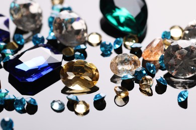 Photo of Different beautiful gemstones for jewelry on mirror surface