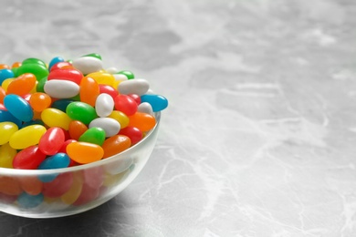 Bowl of delicious jelly beans on table. Space for text