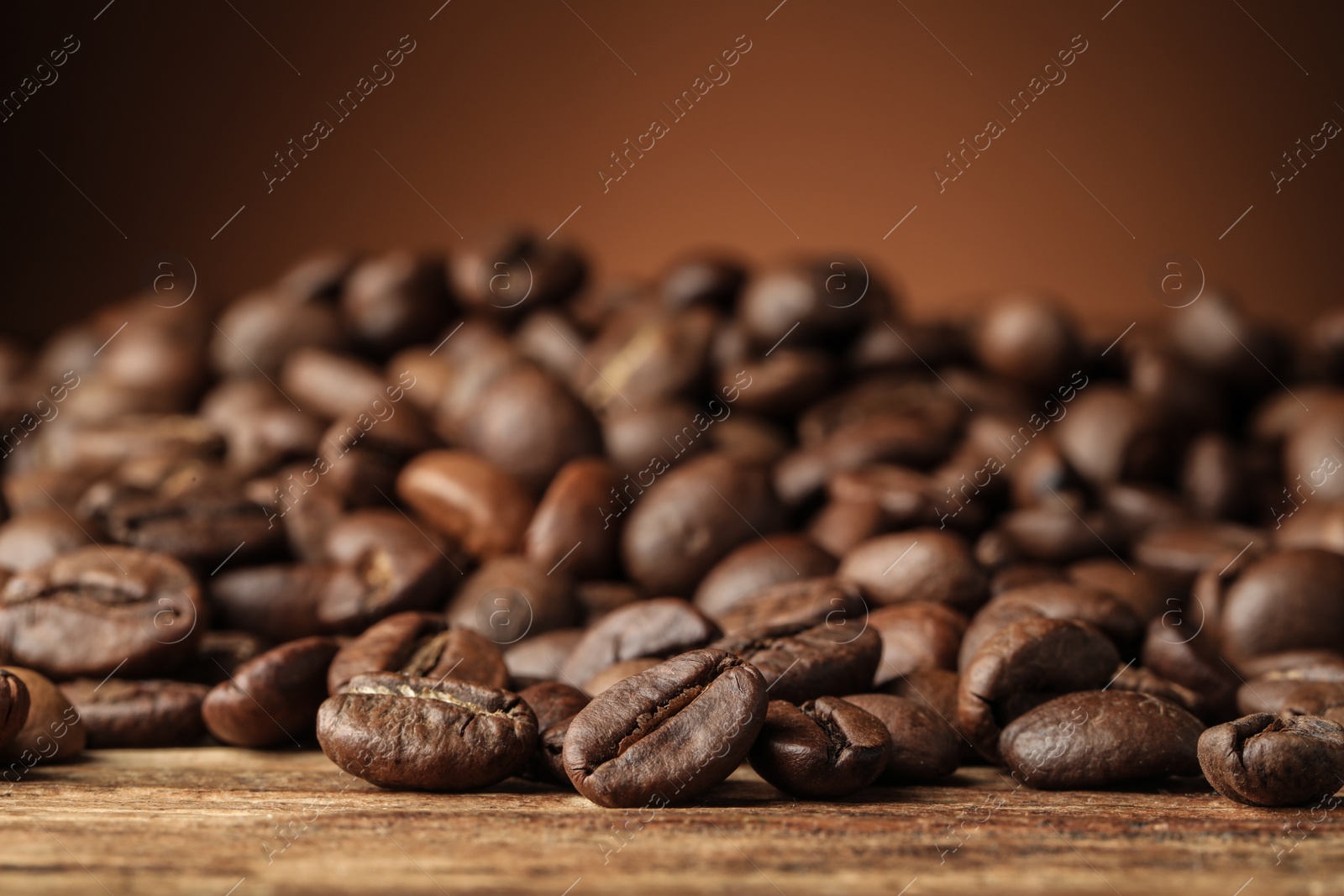 Photo of Many roasted coffee beans on wooden table, closeup