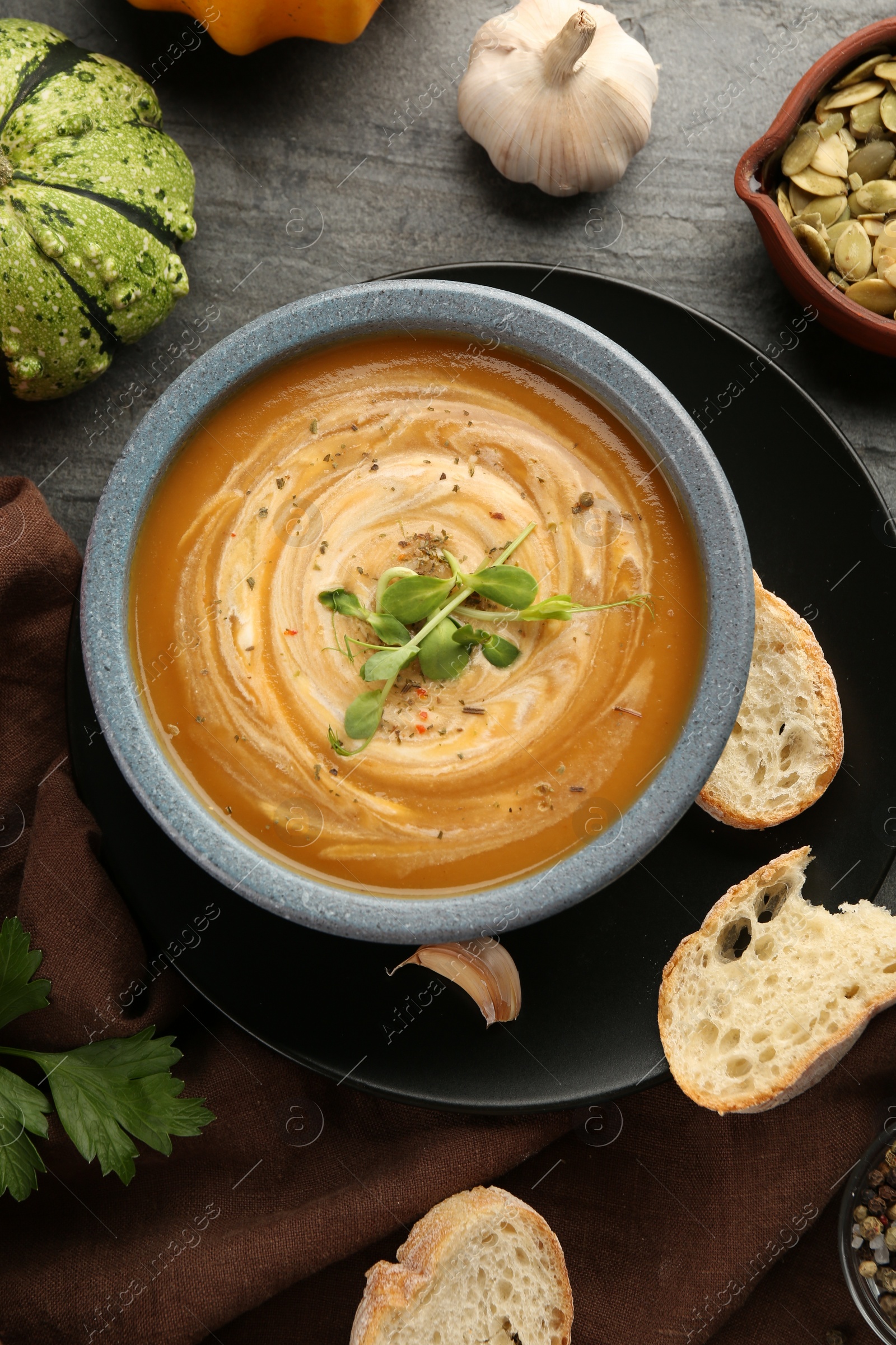 Photo of Flat lay composition with bowl of delicious pumpkin soup on grey textured table