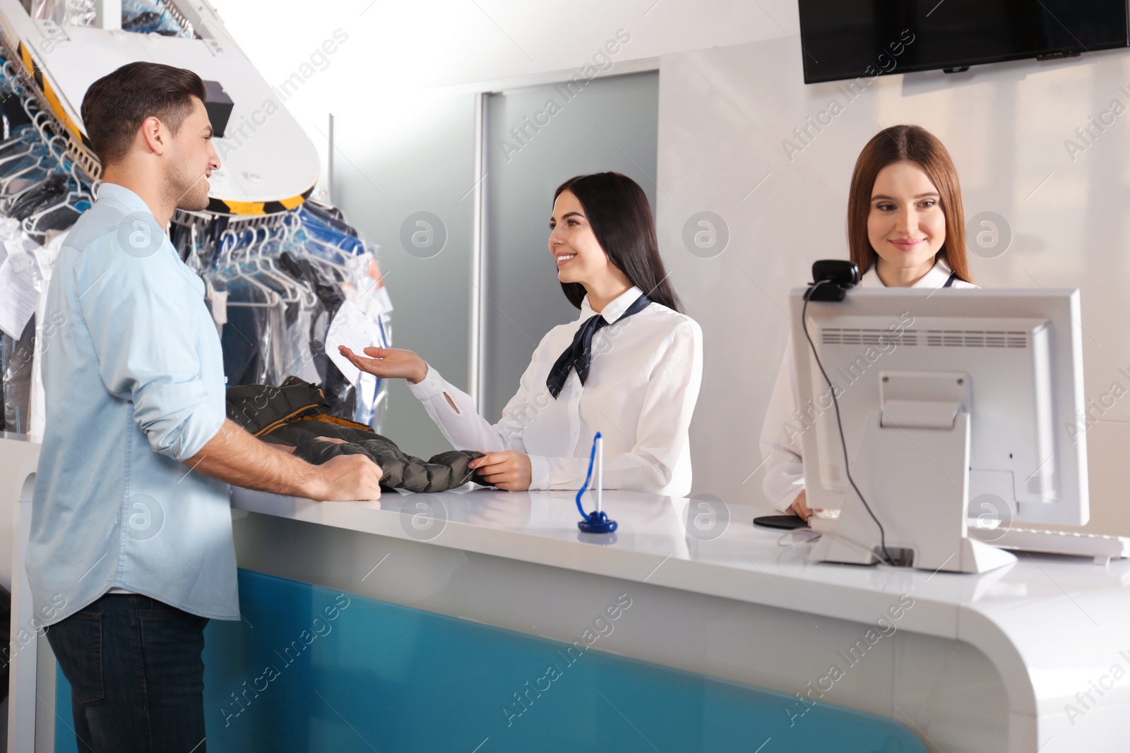 Photo of Female employees working with client at dry-cleaner's