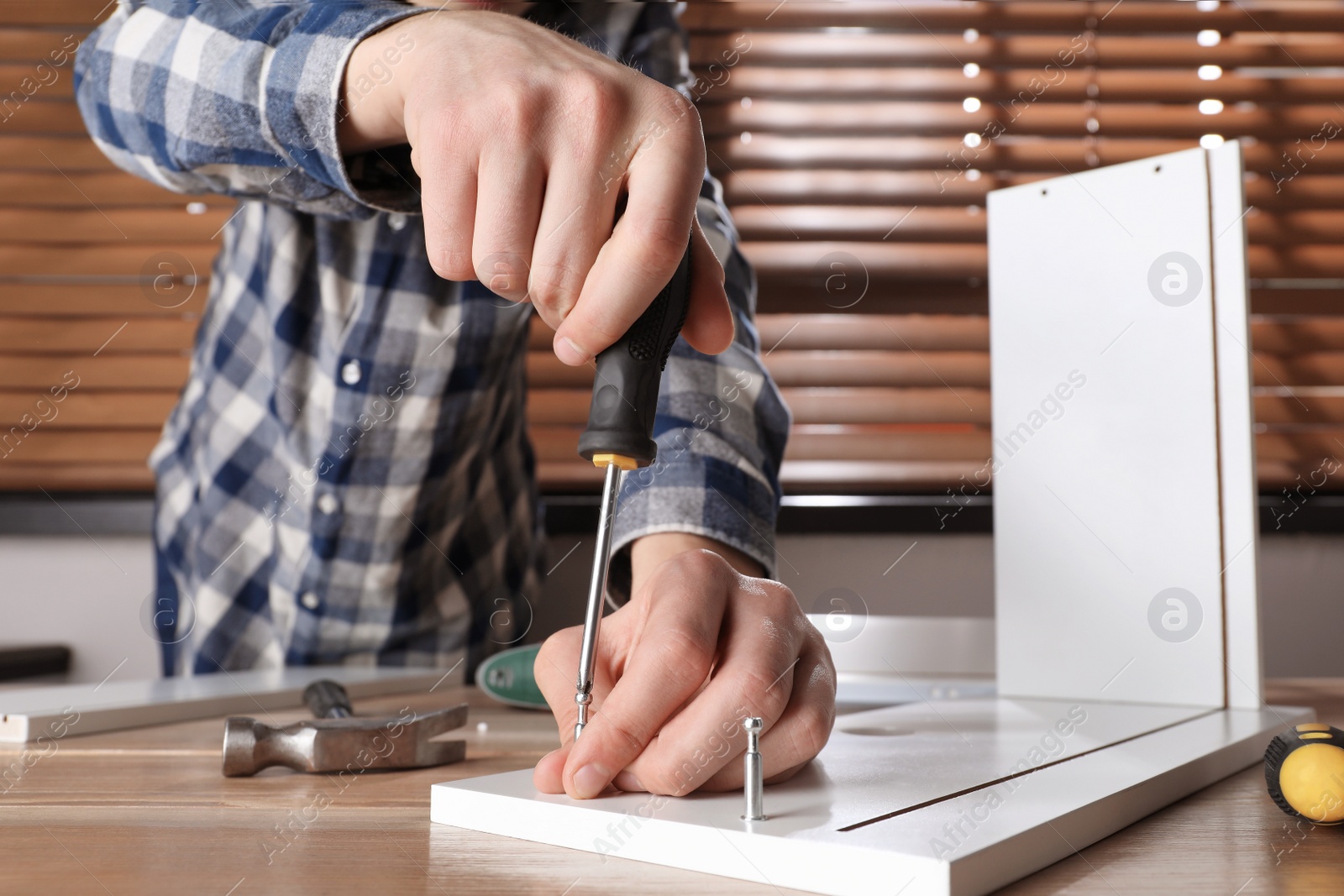 Photo of Man assembling furniture at table indoors, closeup