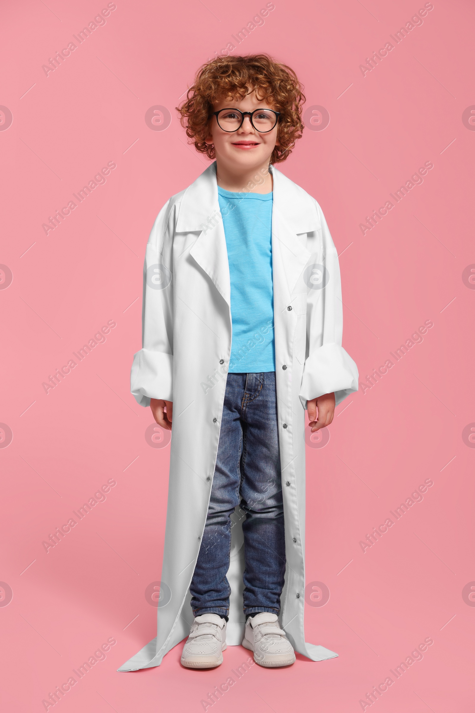 Photo of Full length portrait of little boy in medical uniform and glasses on pink background