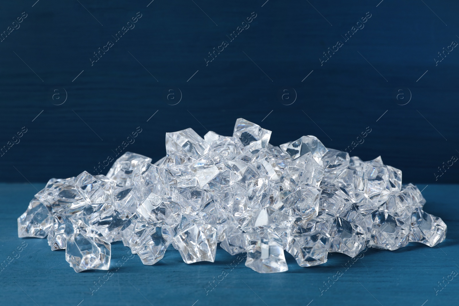 Photo of Pile of crushed ice on blue wooden table