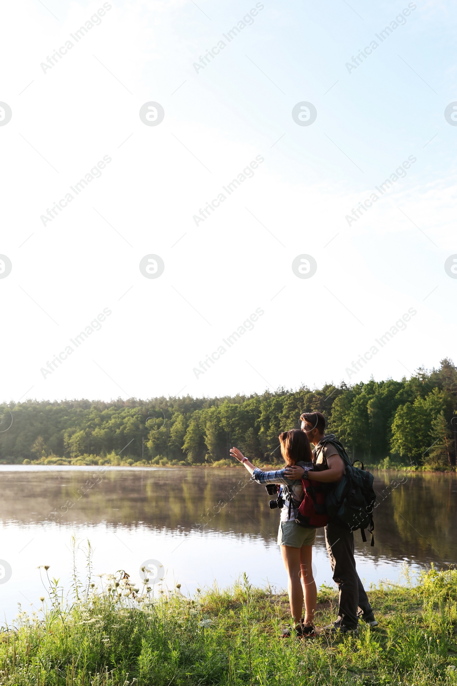 Photo of Young couple on shore of beautiful lake. Camping season