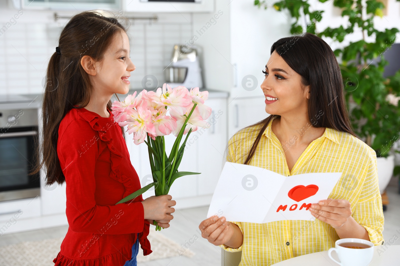 Photo of Daughter congratulating her mom in kitchen. Happy Mother's Day