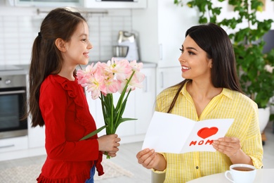 Photo of Daughter congratulating her mom in kitchen. Happy Mother's Day