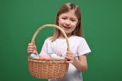 Photo of Easter celebration. Cute girl with basket of painted eggs on green background