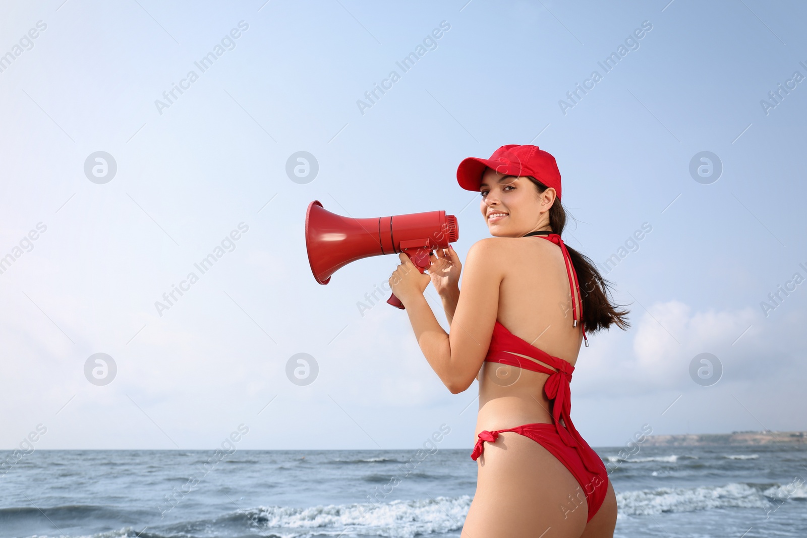 Photo of Beautiful young lifeguard with megaphone near sea