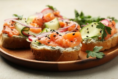 Photo of Tasty canapes with salmon served on light grey table, closeup