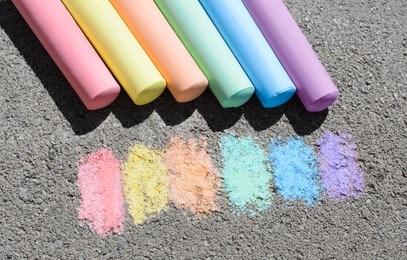 Photo of Colorful chalk sticks and strokes on asphalt outdoors, above view