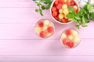 Photo of Glasses of melon and watermelon ball cocktail on pink wooden table, flat lay. Space for text
