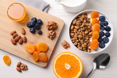 Delicious granola with fruits on white wooden table, flat lay