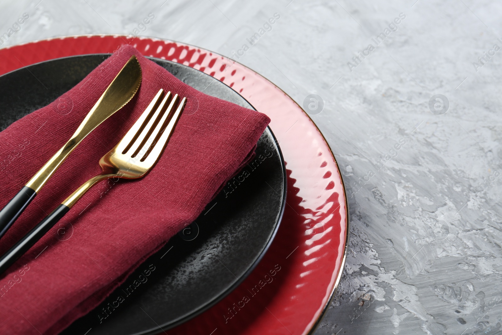 Photo of Clean plates, cutlery and napkin on gray table, closeup. Space for text