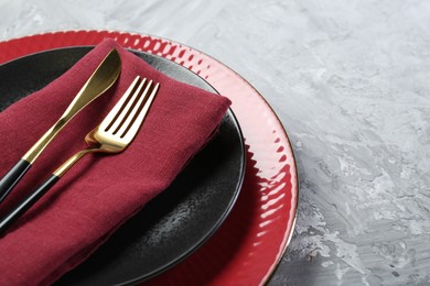 Photo of Clean plates, cutlery and napkin on gray table, closeup. Space for text