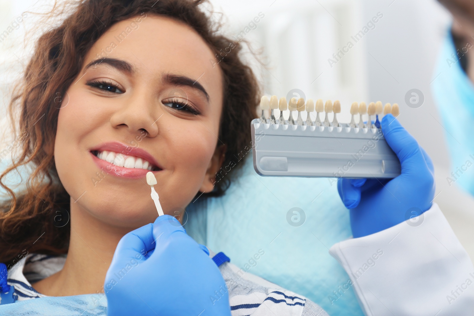 Photo of Dentist matching patient's teeth color with palette in office