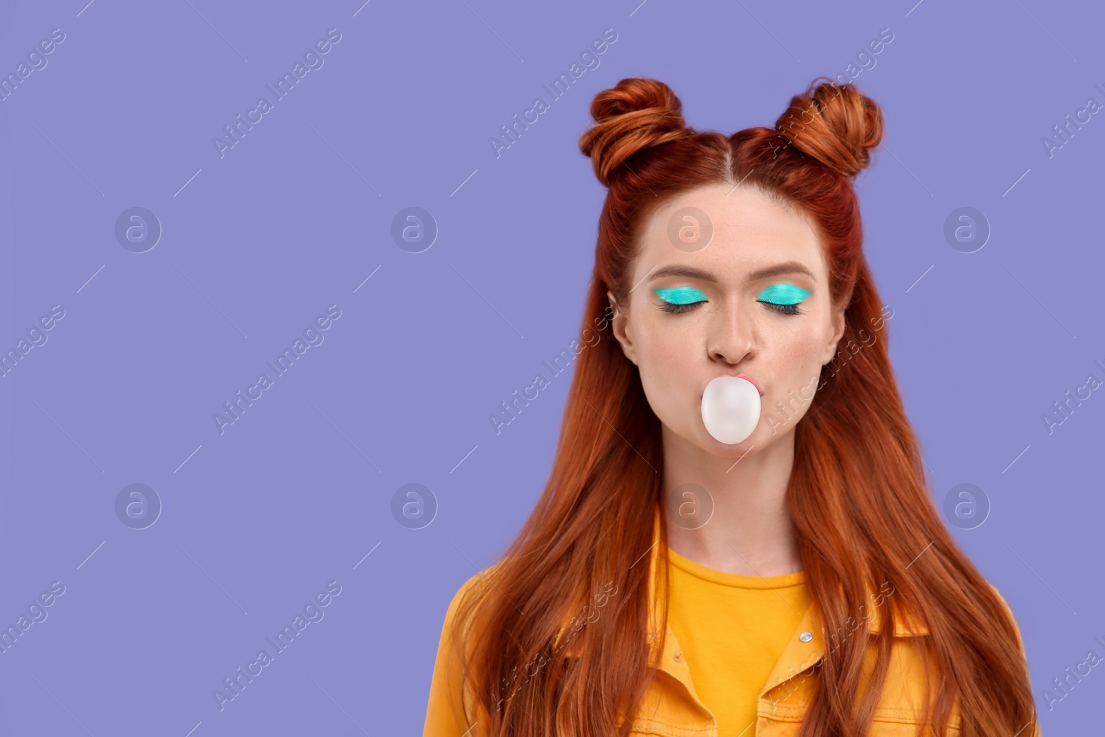 Photo of Beautiful woman with bright makeup and closed eyes blowing bubble gum on violet background. Space for text