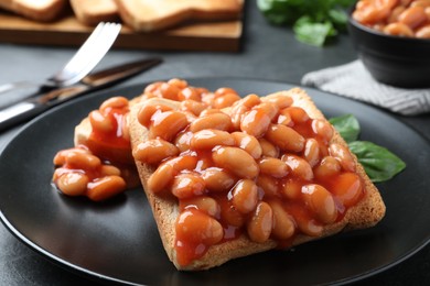 Photo of Toasts with delicious canned beans on black table, closeup