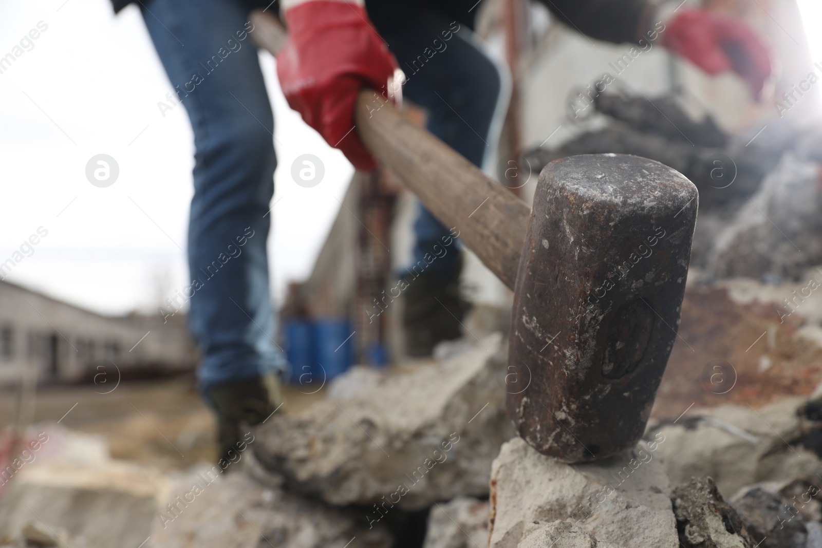 Photo of Man breaking stones with sledgehammer outdoors, selective focus