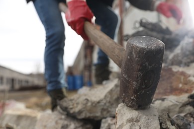 Photo of Man breaking stones with sledgehammer outdoors, selective focus