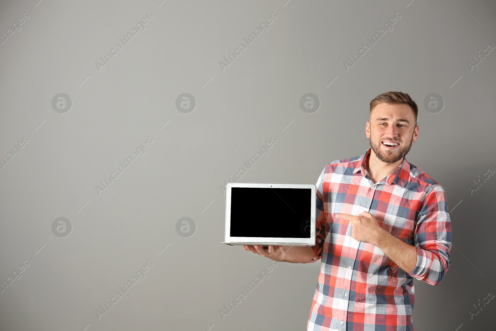 Photo of Portrait of handsome man with laptop on color background