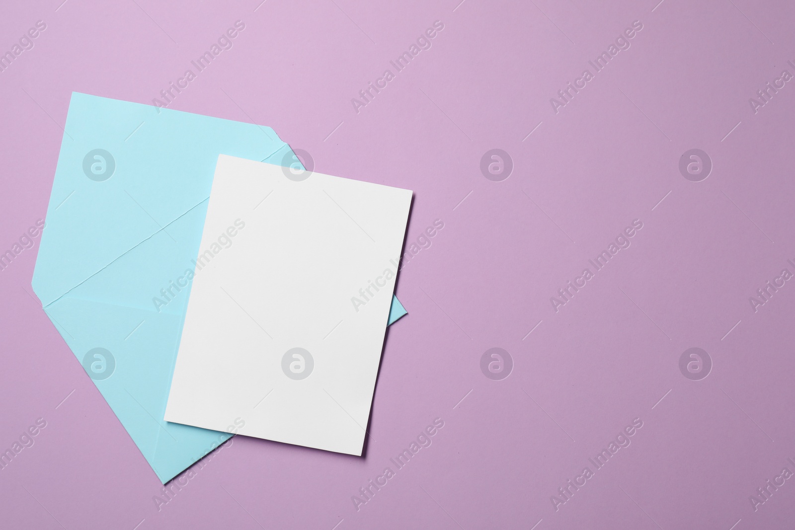 Photo of Letter envelope and card on violet background, top view. Space for text