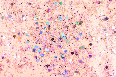 Photo of Shiny glitter on light pink background, top view