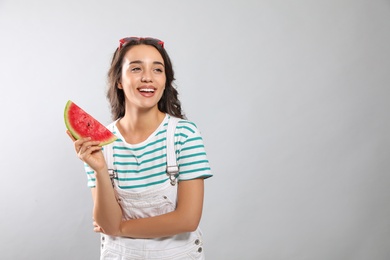 Beautiful young woman with watermelon on grey background. Space for text