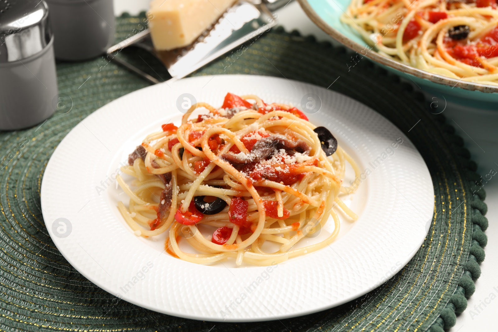 Photo of Delicious pasta with anchovies, tomatoes and parmesan cheese served on white table