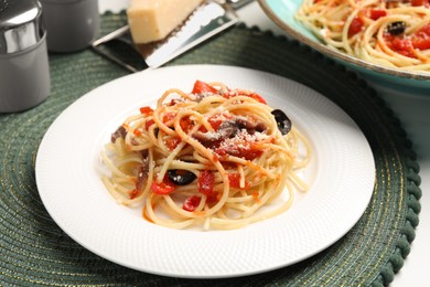 Photo of Delicious pasta with anchovies, tomatoes and parmesan cheese served on white table