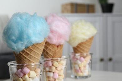 Sweet cotton candies in waffle cones and marshmallows indoors, closeup. Space for text