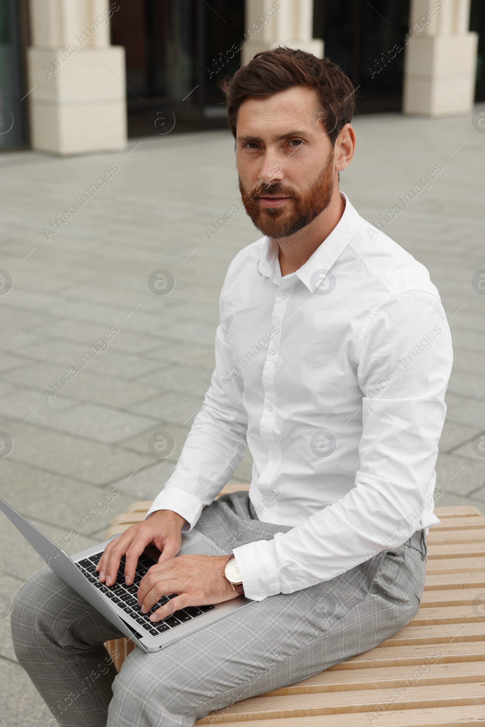 Photo of Handsome businessman with laptop on city street