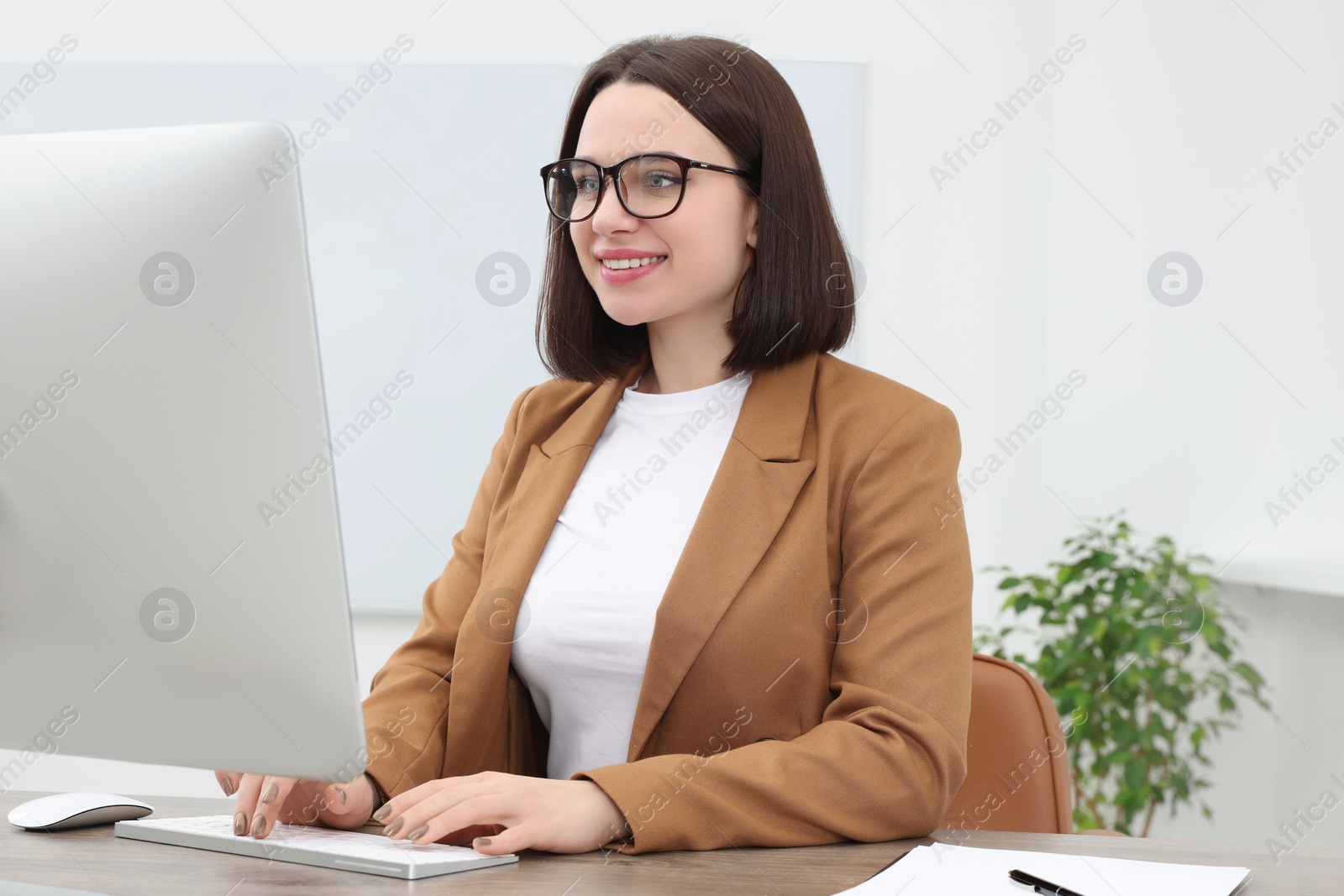 Photo of Happy young intern working with computer at table in modern office