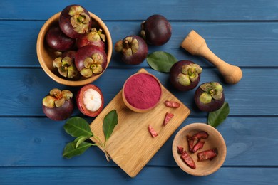 Photo of Purple mangosteen powder and fruits on blue wooden table, flat lay